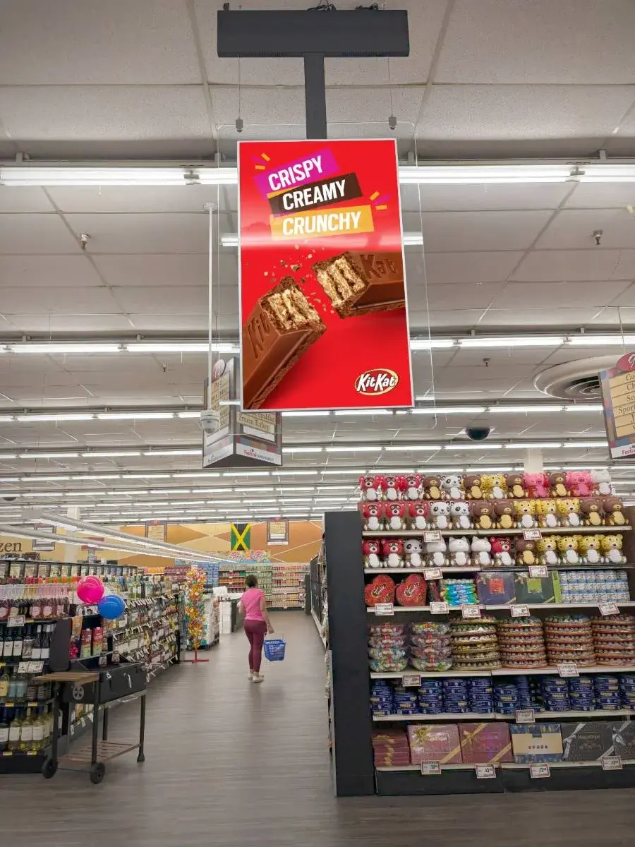 A digital advertising screen above the shopping aisles in a retail store